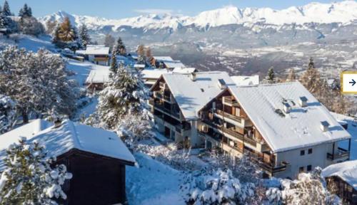 uma casa coberta de neve com montanhas ao fundo em tHE Eagle Nest Duplex - Your Mountain Retreat em Chalais