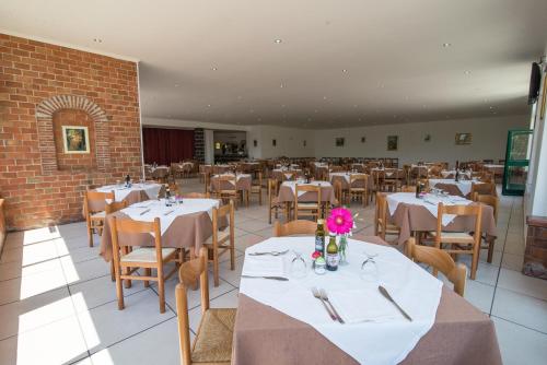 a restaurant with white tables and chairs with pink flowers at Villaggio Alkantara in Giardini Naxos