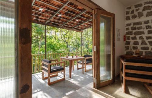 a dining room with a table and chairs on a balcony at Jungle stay by Bilwa Estate in SanivÄrsante