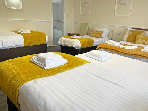 a room with three beds with towels on them at The President Hotel in Blackpool