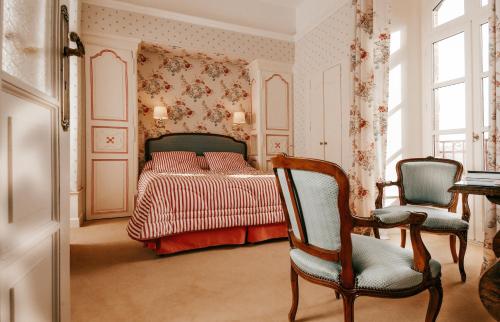 a bedroom with a bed and two chairs at Castel Novel in Varetz