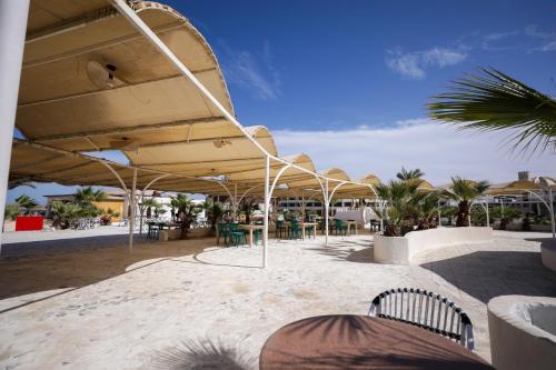 a patio with tables and chairs under a large umbrella at Calimera Blend Paradise in Hurghada