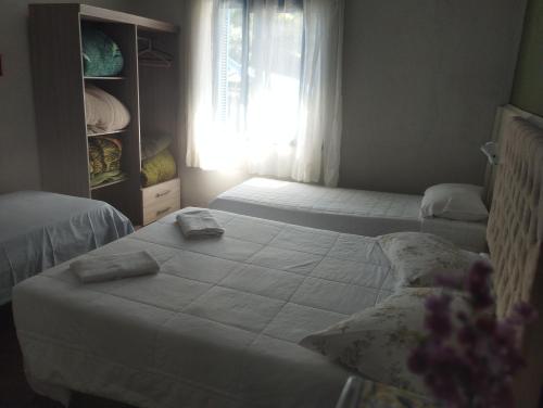 1 dormitorio con 2 camas y ventana en Pousada águia da serra, en Gramado