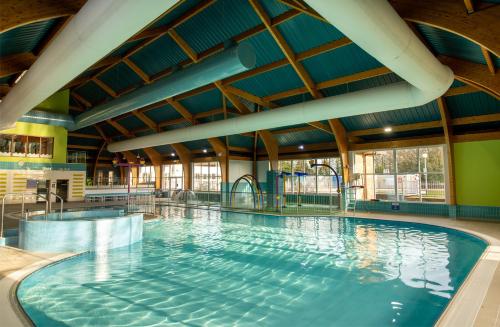a large indoor swimming pool with blue water at Forest Getaway, sleeps 6 at Bashley, leisure PASS included in New Milton