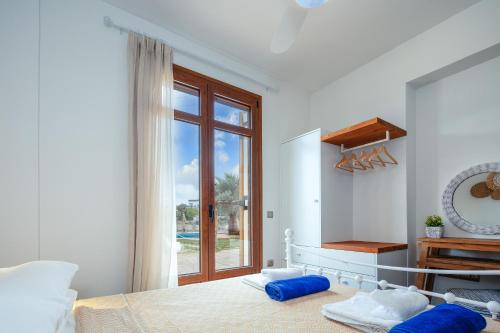 a white bedroom with a bed and a window at Saridakis Villa, a multi-generational Retreat, By ThinkVilla in Roussospítion