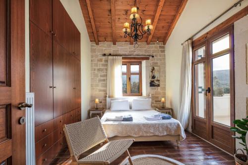 RoussospítionにあるSaridakis Villa, a multi-generational Retreat, By ThinkVillaのベッドルーム1室(ベッド1台、椅子、窓付)