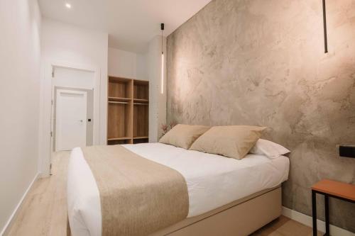 カラバカ・デ・ラ・クルスにあるRINCON DE LA CRUZ 2Bの白いベッドとコンクリートの壁が備わるベッドルーム1室が備わります。