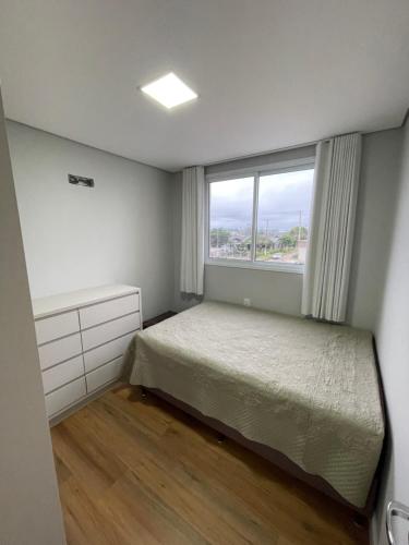 a small bedroom with a bed and a window at Apartamento completo para veraneio in Torres
