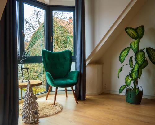 a green chair in a room with a window at AMAO-Green I 90qm I Zentrum I Maisonette I Dachterrasse I King-Size Boxspringbetten I EuropaPark in Lahr