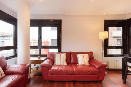 a red leather couch in a living room with windows at Laboa - baskeyrentals in Lekeitio