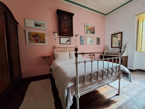 ein Schlafzimmer mit einem Bett in einem Zimmer mit rosa Wänden in der Unterkunft Rafalias Mansion in Hydra