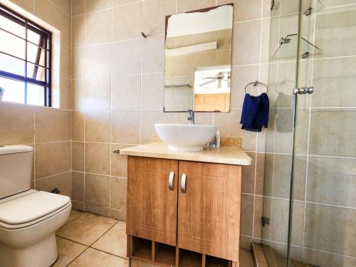 a bathroom with a sink and a toilet and a shower at Spekboom Beach Apartments in Jeffreys Bay
