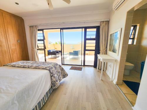 a bedroom with a bed and a view of a balcony at Spekboom Beach Apartments in Jeffreys Bay