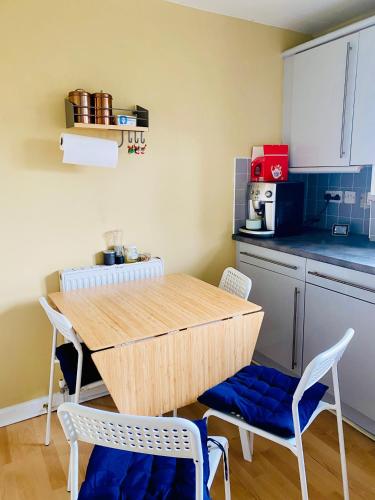 uma cozinha com uma mesa de madeira e cadeiras num quarto em cozy room in Edinburgh em Edinburgo