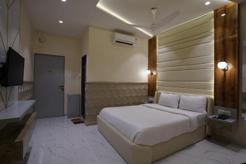 a bedroom with a large white bed and a television at Palm Springs Beach Resort - Gorai in Mumbai