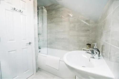a white bathroom with a sink and a shower at K Suites - Laurell Ville in Amley