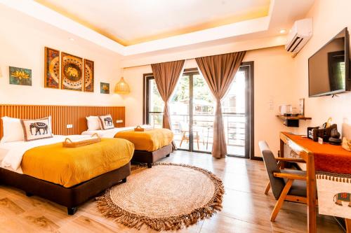 a hotel room with two beds and a television at Molly Resorts in Puerto Galera