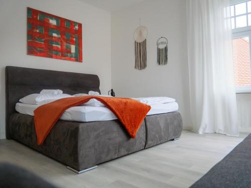 Un dormitorio con una cama con una manta naranja. en AMAO-Brown I 85qm I Zentrum I KingSizeBett I Parkplatz I Am Storchenturm, en Lahr