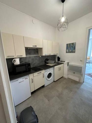 une cuisine avec des armoires blanches et une laveuse et une sécheuse dans l'établissement Grand appartement Cordier, à Rouen