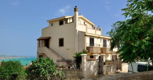 a large white house with a fence in front of it at B&B Nicole in Palma di Montechiaro