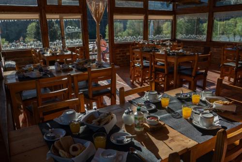 un comedor con mesas y sillas con comida. en El Hostal del Rio en Aluminé