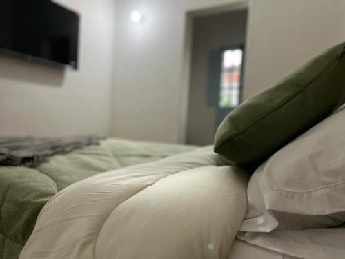 a bed with green pillows on top of it at Encanto Azul en Villa in Villa de Leyva