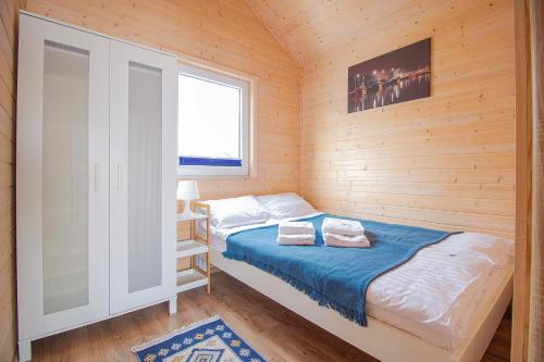 niewielka sypialnia z łóżkiem i oknem w obiekcie Morska Przystań Darłówko w Darłówku