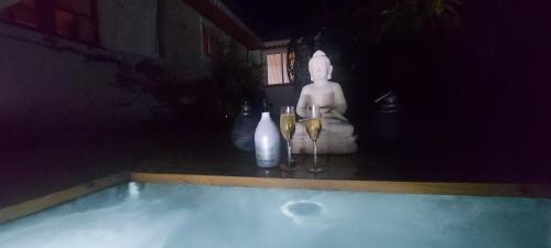 a statue sitting next to a swimming pool with wine glasses at Villa Ananda in Cilaos