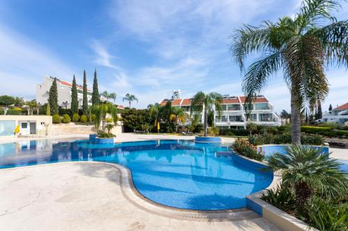a large swimming pool with palm trees and buildings at Bay View Gardens by TrulyCyprus in Limassol