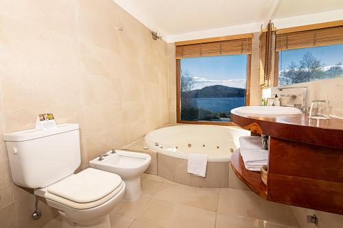 La salle de bains est pourvue de toilettes, d'un lavabo et d'une baignoire. dans l'établissement Rochester Bariloche Suites & Spa, à San Carlos de Bariloche