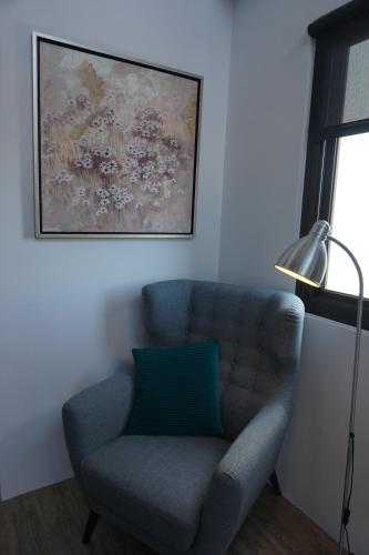 a blue chair in a living room with a painting at Double Egg Yolk Living Space in Dongshan