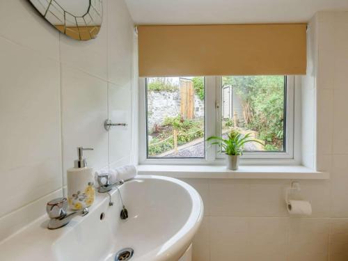 a white bathroom with a sink and a window at 3 Bed in Ferryside 88784 in Ferryside