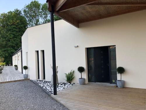 um edifício branco com uma porta preta e vasos de plantas em Le Parc du Château em Hermonville