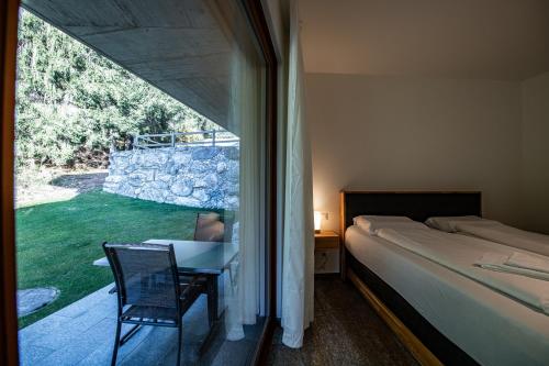 um quarto com uma cama, uma mesa e uma janela em Putzprinz Gujan Apartment Whispering Pines em Laax