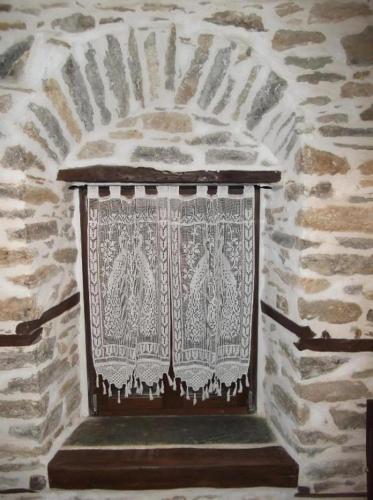 a window in a stone wall with a curtain at Archontiko Michael Pelion in Vizitsa