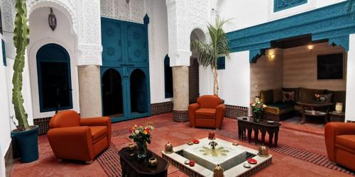 um átrio com cadeiras laranja e uma sala de estar em Riad Dar Alhambra em Marrakech