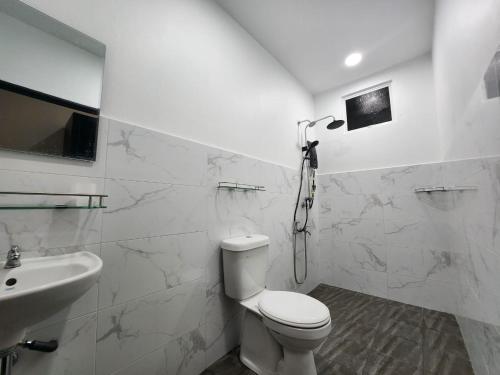 biała łazienka z toaletą i umywalką w obiekcie Restu Villa Homestay w mieście Tuaran