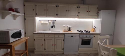 a kitchen with white cabinets and a sink and a microwave at Villa Carmela - Centro Arezzo in Arezzo