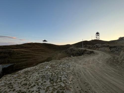 a dirt road with a lighthouse on a hill at Himalayan Canvas khajjiar in Khajjiar 