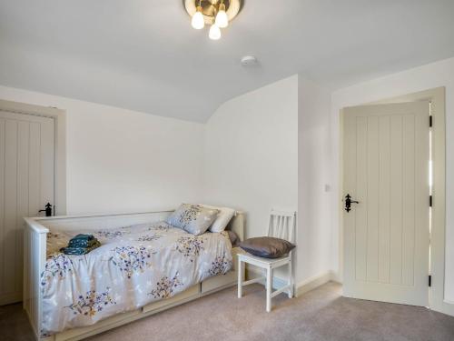 a white bedroom with a bed and a chair at Teach Eile, Clifden in Clifden