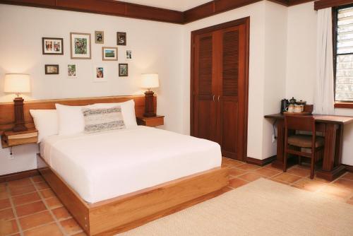 a bedroom with a white bed and a desk at Hidden Valley Wilderness Lodge in San Ignacio