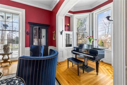 a living room with a piano and red walls at The Hamilton Hoppin House in Middletown