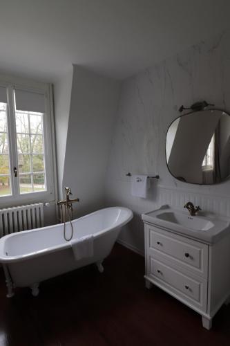 une salle de bain avec une baignoire, un lavabo et un miroir dans l'établissement Le Domaine Saint Ange, à Friville-Escarbotin