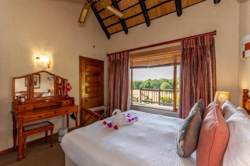um quarto com uma cama, uma secretária e uma janela em Kruger Park Lodge Unit No. 516 em Hazyview