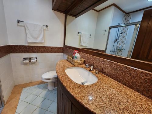 a bathroom with a sink and a toilet and a mirror at House of Joe - Camp Johnhay in Baguio