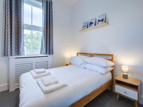 a bedroom with a bed with white sheets and a window at Pass the Keys Comfortable flat near Southend in Westcliff-On-Sea