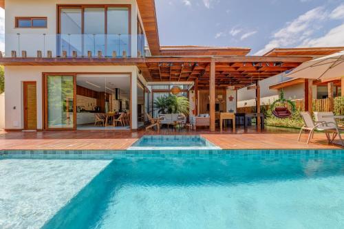 a villa with a swimming pool and a house at Casa Ofir - Alto Padrão in Praia do Forte