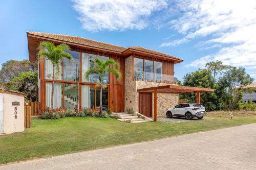 a house with a car parked in front of it at Casa Ofir - Alto Padrão - Serviços Inclusos in Praia do Forte