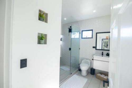 a bathroom with a toilet and a glass shower at Apartamentos Cristal in Quepos