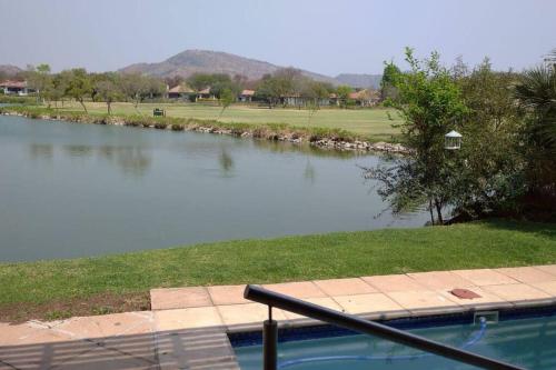 una piscina junto a un cuerpo de agua en Cosy home in Pecanwood lake view - Hartbeesport, en Hartbeespoort